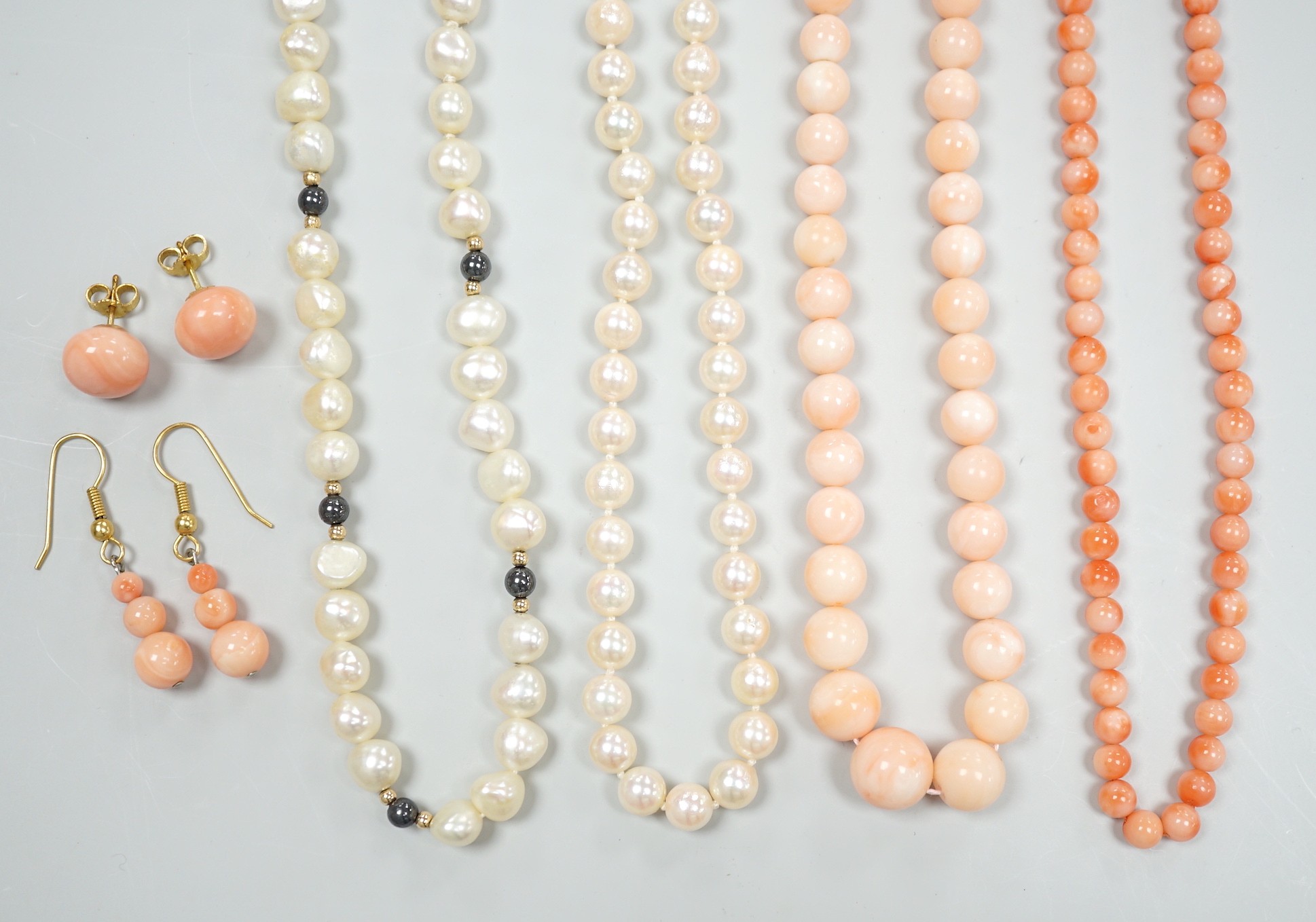 Two modern single strand cultured pearl necklaces, both with 375 clasp, one with hematite beads, longest 42cm, together with two modern coral bead necklaces, one with pair of matching drop earrings.